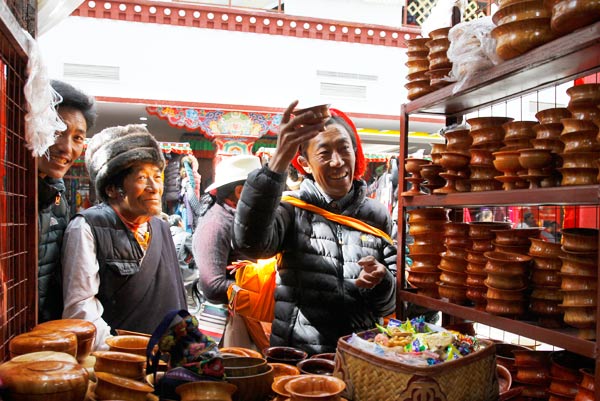 A traveler from the Kham region in the east of the Tibet autonomous region chooses bowls at Barkhor Shopping Mall in Lhasa on Friday. The modern mall houses about 3,000 street vendors relocated from Barkhor Street. WANG HUAZHONG / CHINA DAILY