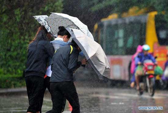 Local residents walk in rain against strong wind as Typhoon Haiyan approaches in Haikou, capital of south China's Hainan province, Nov. 10, 2013.(Xinhua/Guo Cheng)