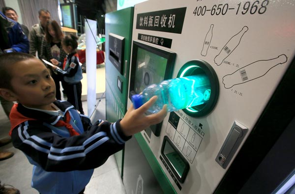 Students place empty bottles in a reverse vending machine, which accepts used containers in exchange for money to the user, at the primary school attached to Capital Normal University. Hao Yaxin/For China Daily