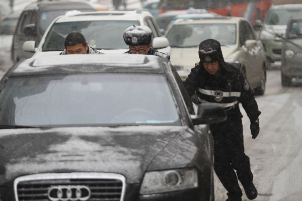 Police officers help move a stalled car as the first heavy snow shut down expressways and delayed flights in Harbin, Heilongjiang province, on Sunday. Wang Tienan / for China Daily