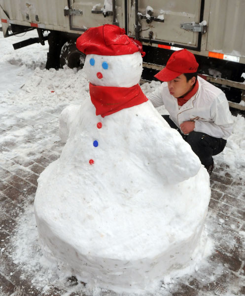 A worker with a fast-food restaurant takes advantage of the early snowfall in Harbin on Sunday. Liu Yang / for China Daily