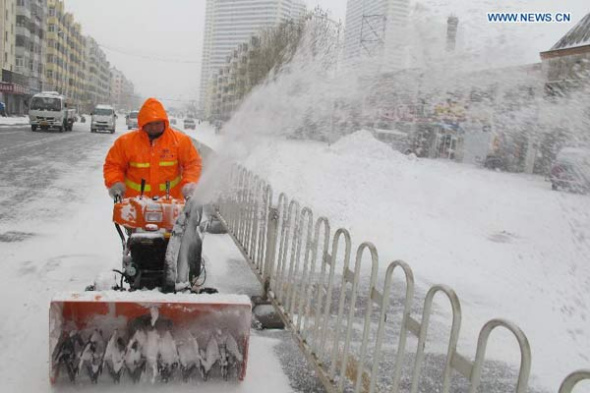 A sanitation worker clears the snow on a road in Harbin City, capital of northeast China's Heilongjiang Province, Nov. 17, 2013. Traffic and schools have been hit in northeast China's Heilongjiang and Jilin provinces as a blizzard closed expressways and schools and delayed flights. (Xinhua/Zhang Qingyun)