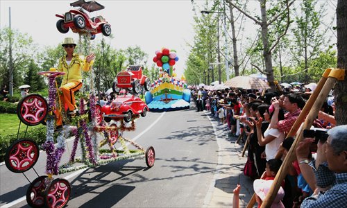 Visitors of the 9th China International Garden Expo take pictures from the side of a street as they watch a parade in the expo park in Beijing's Fengtai district. Photo: Courtesy of the organizing committee of the expo