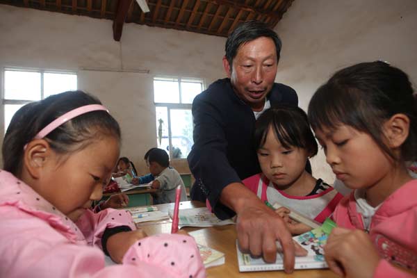 Xiong Gaoxiang, a teacher in Shanqingmiao, Sichuan province, instructs students in class. Xiong, 58, is one of only three teachers at the village school and has been teaching for more than 30 years. The government has been creating more benefits to keep teachers in the countryside. Lan Zitao / For China Daily