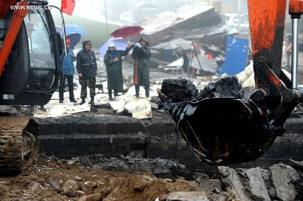 An excavator is used at the site of a pipeline explosion in Qingdao Development Zone, in Qingdao, east China's Shandong Province, Nov. 24, 2013. A leaking pipeline caught fire and exploded on Friday morning in Huangdao District of Qingdao. The death toll in the explosion rose to 52 and the search effort is still ongoing. (Xinhua/Li Ziheng) 