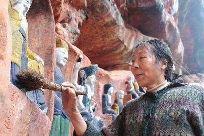 Kang Guangqing cleans Buddha statues Xuyong county, Sichuan province.[Photo by Zhang Xun/West China Metropolis Daily ]