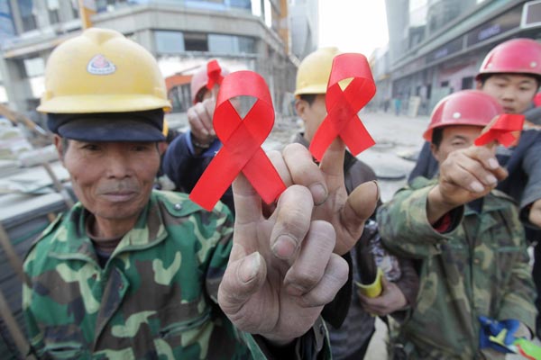 Migrant workers at a construction site in Weifang, Shandong province, on Saturday, display red ribbons, signifying solidarity with HIV/AIDS patients. Volunteers gave them brochures on AIDS prevention on the eve of World AIDS Day. Zhang Chi / for China Daily 