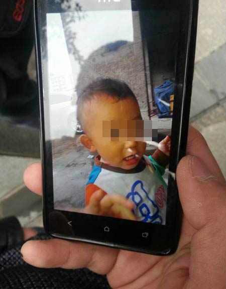 Li Shuyong's mobile phone displays a picture on Thursday of his 18-month-old son who was attacked in an elevator. Luo Wangshu / China Daily
