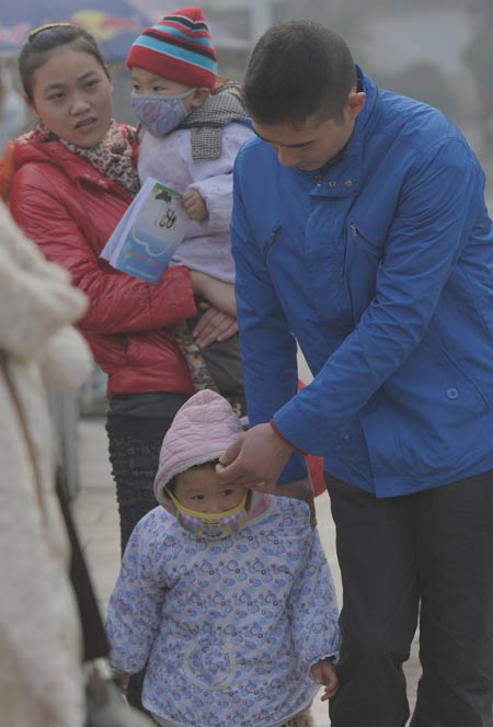 Parents in Nanjing try to protect their children from heavy air pollution in the city on Thursday. Schools were closed on Thursday and have been ordered to close on Friday. Yang Duoduo/For China Daily