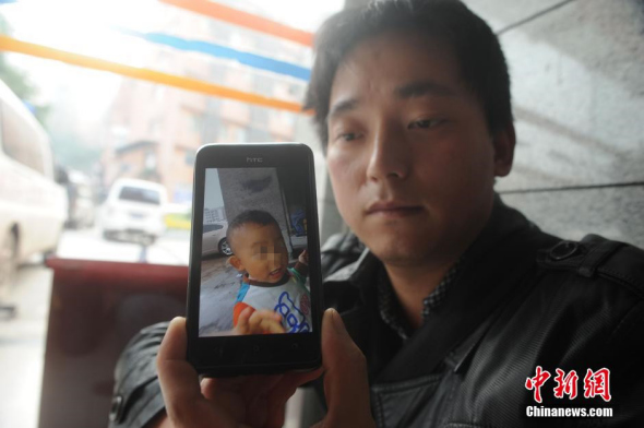 Father shows a photo of Li Xinyuan. [Photo: China News Service]