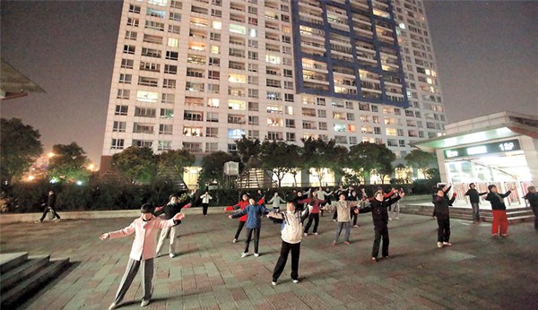 People dance in a public square in front of a residential community near a Metro station exit on Yuyuan Road. (Wang Rongjiang) 