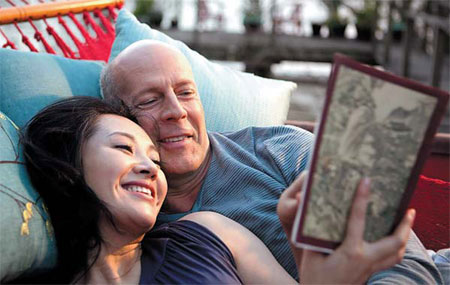 US film star Bruce Willis (right) reads a book with Chinese actress Xu Qing in a scene from the movie Looper. Hollywood has paid increasing attention to the Chinese market, which is expected to be the world's biggest box office in less than 10 years. Provided to China Daily