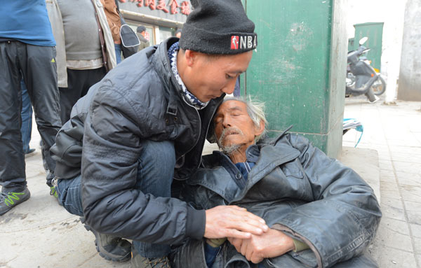 A Lanzhou resident surnamed Li helps an elderly man who was hit by a car in the capital of Gansu province on Nov 25. Li tried to contact the man's family, but could not reach them. The man was later sent to a senior citizens' home. PEI QIANG / FOR CHINA DAILY