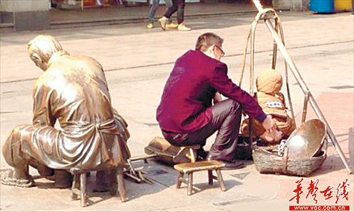 An unidentified man helps a child defecate in a bronze statue on a pedestrian street in Changsha, Hunan Province on December 9. The photo was met with public outcry over public defecation. Photo: voc.com.cn 