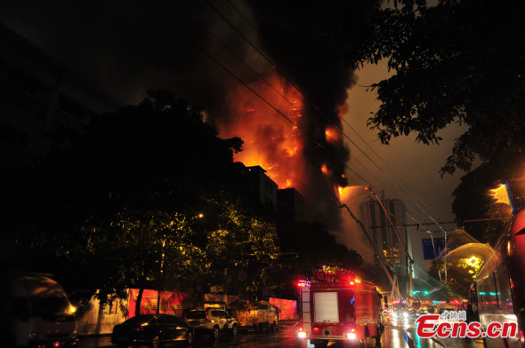 Fire is seen raging in a high-rise building in downtown Guangzhou, capital of south China's Guangdong province, on the night of Dec 15, 2013. Several fire engines have arrived at the site trying to put out the blaze. [Photo: China News Service / Chen Jimin]