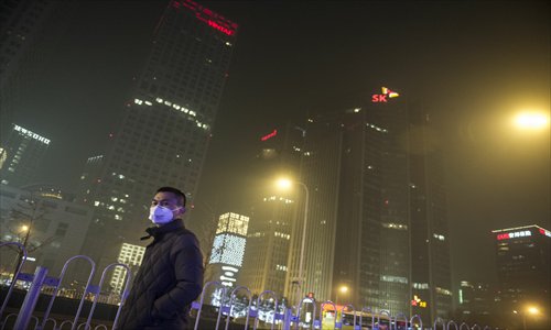 A pedestrian wears a mask as he walks in Beijing's CBD during a heavy bout of smog earlier this month. Photo: Li Hao/GT