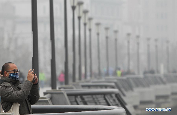 A visitor takes photo at the Bund in Shanghai, east China, Dec. 9, 2013. Heavy smog and fog continued to hit Shanghai on Monday. (Xinhua/Pei Xin) 