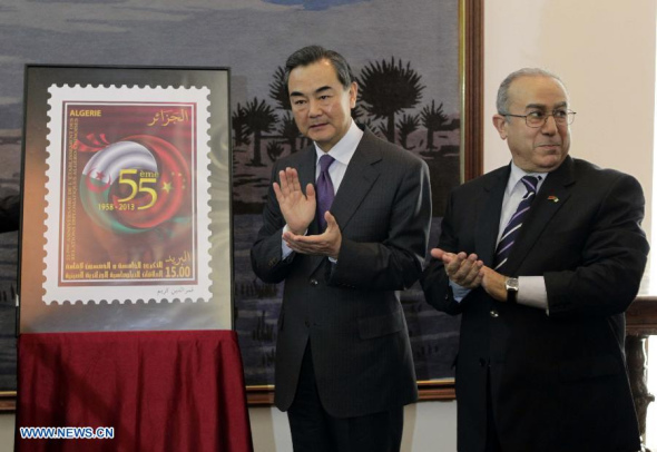 Chinese Foreign Minister Wang Yi (L) and Algerian Foreign Minister Ramtane Lamamra attend a launching ceremony of the stamp commemorating the 55th anniversary of establishment of diplomatic relations between China and Algeria in Algiers, Algeria, Dec. 21, 2013.(Xinhua/Mohamed Qadri)