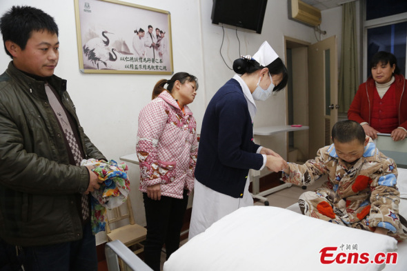 A 6-year-old boy, who suffers from a disfigured face resulting from a traffic accident, prepares for his surgery at a hospital in Xi'an, northwest China's Shaanxi province on Dec 23, 2013. [Photo: China News Service / Ren Weifeng]