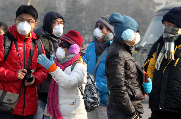Tourists wear filter masks in Beijing on Wednesday to avoid inhaling pollutants. Hebei, Beijing, Tianjin, and five provinces in central and eastern China have suffered heavy smog recently. Yan Xiaoqing / For China Daily