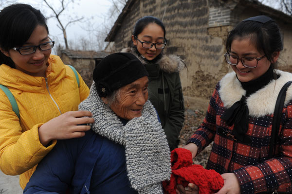 Students from a teachers' college in Fuyang, Anhui province, donate scarves, woolen sweaters and clothing to impoverished villagers and children to help them cope with the cold winter. Wang Biao / For China Daily