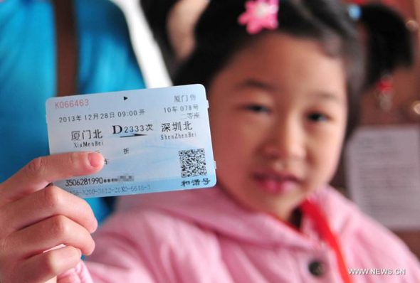 A passenger of bullet train D2333 shows a ticket at Xiamen North Railway Station, in Xiamen, capital of southeast China's Fujian Province, Dec. 28, 2013. The Xiamen-Shenzhen High Speed Railway, a corridor on the southeast coast of China, officially opened to traffic on Saturday. (Xinhua/Lin Shanchuan)