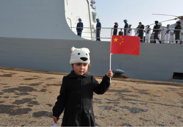 A girl poses for a photo besides Chinese navy frigate Yancheng in the Cypriot port of Limassol on Saturday. [Photo/Xinhua]