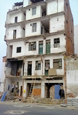 The final remains of an apartment building where residents use ladders to enter their homes stands in Nanning, Guangxi Zhuang Autonomous Region on January 3. The building was partially demolished in a municipal road-widening project. Photo: Beijing Times