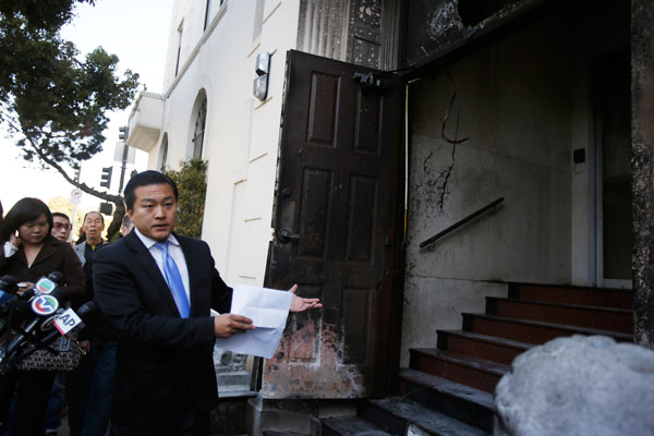 Wang Chuan, a spokesman for the Chinese consulate in San Francisco, points to a damaged door during a news conference after an unidentified person set fire in San Francisco, California January 2, 2014. [Photo/Agencies]