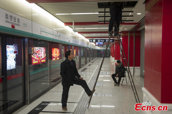 Workers work at Nanluoguxiang Station of Beijing's No 8 subway line on Dec 25, 2013. [Photo: China News Service / Cui Nan]