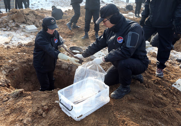 Workers from the Republic of Korea dig up the remains of Chinese volunteer soldiers killed in the Korean War (1950-53) in Paju on Dec 20. Provided to China Daily