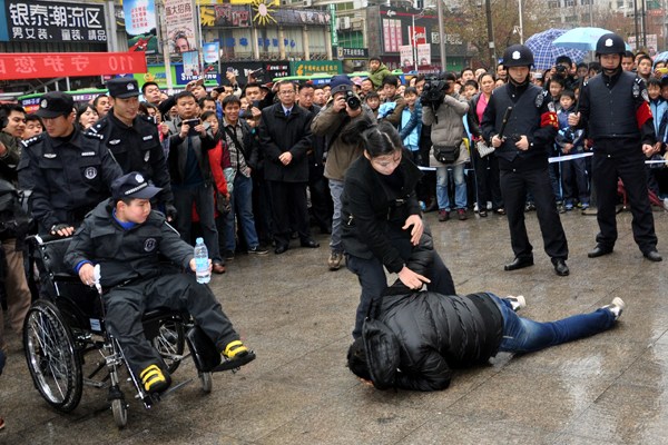 Zou Junyi (left, in wheelchair), who has muscular dystrophy, realized his dream of becoming a police officer in a drill staged by police and volunteers in Xinyu, Jiangxi province, on Saturday. Ao Weibing / for China Daily