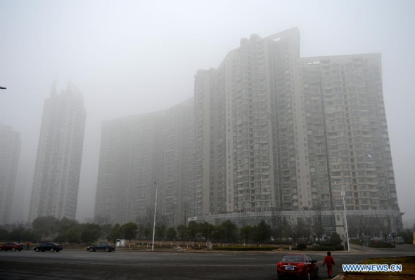 Buildings are blanketed by fog in Nanchang, capital of east China's Jiangxi province, Jan. 14, 2014. The local meteorologic center issued an orange alert for fog on Tuesday. (Xinhua/Zhou Ke)