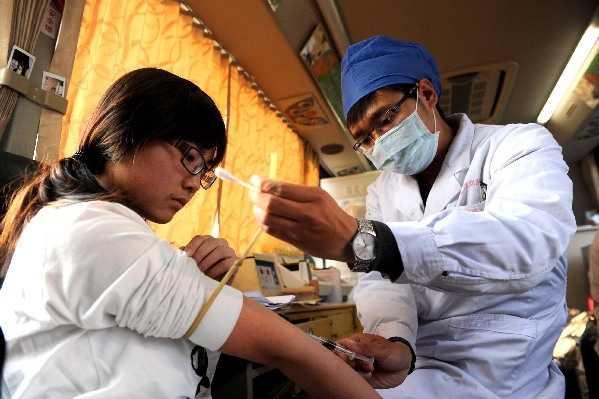 A woman donates blood in a converted vehicle in Beijing's Xidan neighborhood in April 2013. Provided to China Daily