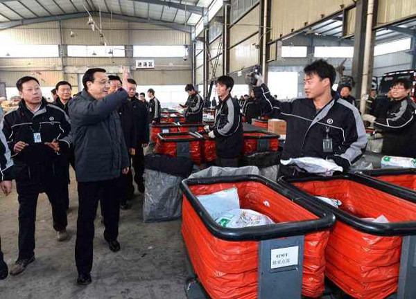 Li Keqiang is waving his hand to workers at the distribution center of domestic courier company SF Express Co in Xi'an, Jan 27, 2014. [Photo/gov.cn]