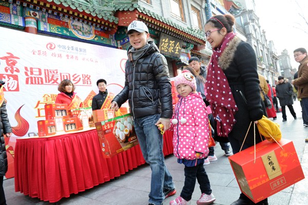 A family in Beijing buys a Quanjude Peking roast duck hamper at Qianmen Pedestrian Street ahead of the Spring Festival holiday. [Jiang Dong / chinadaily.com.cn] 