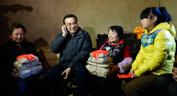 Premier Li Keqiang talks with the father of Yang Kang, a 12-year-old girl, over the phone during a visit to her home in Xunyang county, Shaanxi province, on Monday. Yang's father works in the city and told the premier he will return home in time for Spring Festival. Liu Zhen / China News Service