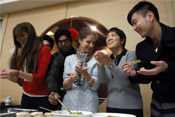 Liu Wei (second right), deputy Party chief of Beijing Language and Culture University, shows Maria Bolocan (second left), a Romanian student how to make dumplings at the school's party to celebrate the coming Spring Festival. Zou Hong / China Daily