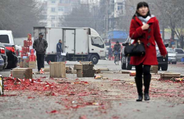 A woman walks past firework paper wastes in Tianjin January 31, 2014. [Photo/Xinhua]