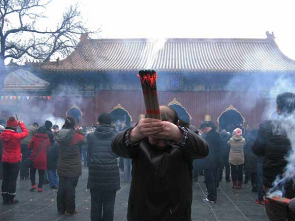 A man prays for good fortune as he holds burning incense on the first day of the Chinese Lunar New Year at Yonghe Lama Temple, in Beijing, January 31, 2014. [Photo by Wu Chuanjing/chinadaily.com.cn]