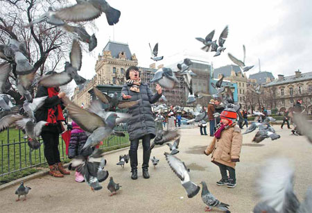 Chinese tourists play in front of Notre-Dame de Paris. Data suggest a record number of them chose to travel abroad during this year's Spring Festival. Provided to China Daily