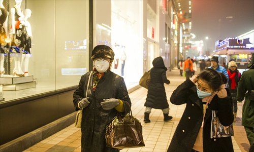 People walking beside a shop in the Wangfujing shopping street in Beijing wear masks to protect against the heavy smog on Thursday. The city has been plagued with high pollution readings over the last week. Photo: Li Hao/GT