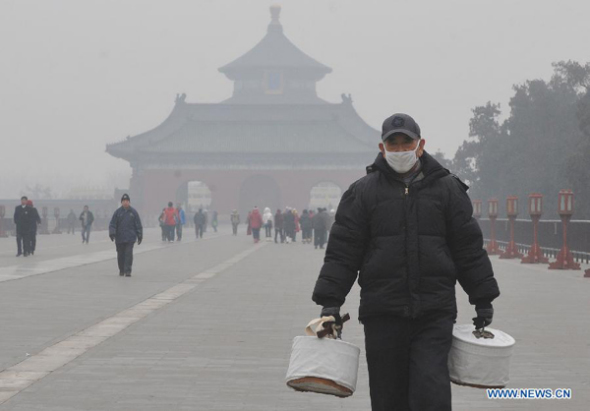 An old man wearing facial mask walks at the Temple of Heaven Park in Beijing, capital of China, Feb 22, 2014. Thick smog shrouding Beijing and its surrounding areas becomes heavier as the capital has raised its four-tiered alert system to orange. (Xinhua/Gong Lei)