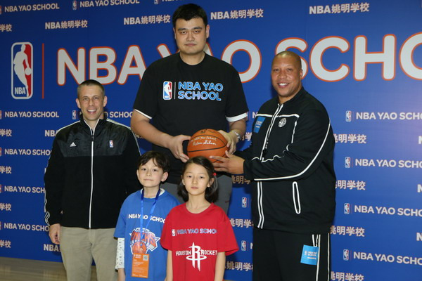 Retired Chinese basketball great Yao Ming (C), NBA China CEO David Shoemaker (L) and US basketball coach Billy Singleton pose with two children at the opening ceremony of the NBA Yao School, a basketball program jointly launched by Yao and the NBA to foster youth development in basketball and life, at the Wukesong Park in Beijing, Feb 22, 2013. [Photo provided to chinadaily.com.cn]