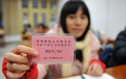 A student shows her seat card in the library in Changsha, capital of central China's Hunan province, Feb 24, 2014. The library provides three rooms for students who prepare to take postgraduate examinations. The seats of the rooms are distributed to colleges based on their needs. Students can get a seat through seat card lottery or sharing a seat with others. The new way of seat assignment saves students' time and reduces the uncouth behavior. (Xinhua/Li Ga)