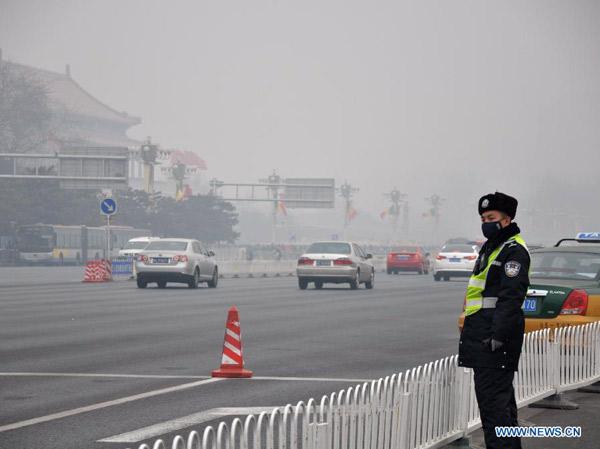 A policeman directs traffic amid fog and smog on Chang'an Street in Beijing, capital of China, Feb 22, 2014. Many cities maintained alert for air pollution on Feb 25 since the fog and smog choked northern and central China days ago. (Xinhua/Wang Junfeng)