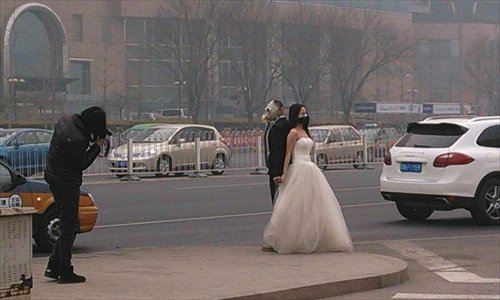 A couple wearing gas masks poses for wedding photos near the Guomao overpass in Beijing's Chaoyang district February 25, as a string of heavy smog days continue to choke many parts of northern China. Photo: weibo.com
