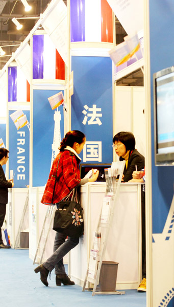 A student visits a booth for details on studying in France at an education fair in Beijing last year. [Photo by Lei Kesi / for China Daily]