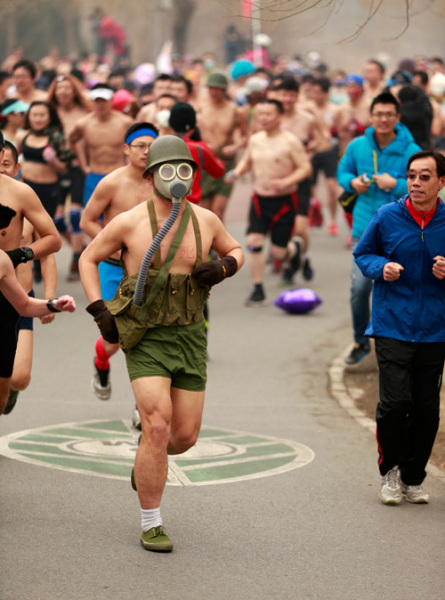 Masks, even a gas mask, are popular among runners attending a "naked run" event at Beijing Olympic Park on Sunday amid heavy smog. The event aims to promote environmental protection awareness. Feng Yongbin / China Daily 