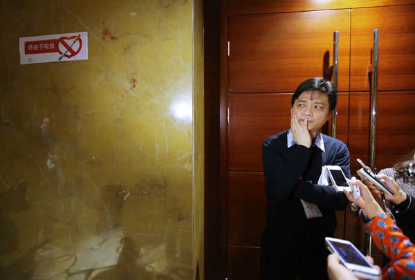 Cui Yongyuan, a CPPCC member, stands near a sign that reads Thanks for not smoking, as he waits to be interviewed. [Jiang Dong/China Daily]